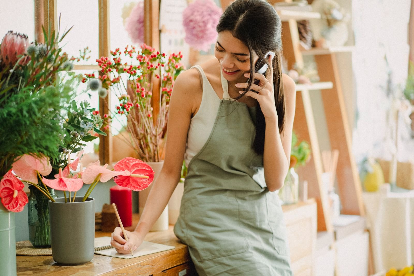 Une prestataire, souriante, au téléphone dans sa boutique, prend une réservation (photo provisoire)